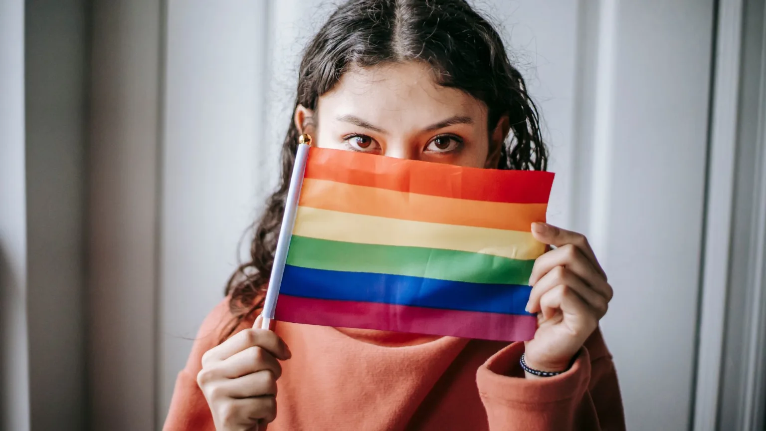 Young ethnic woman with colorful LGBT flag